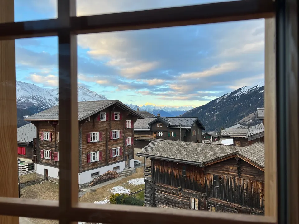 Fensterblick auf Walliser Holzhäuser im Winter